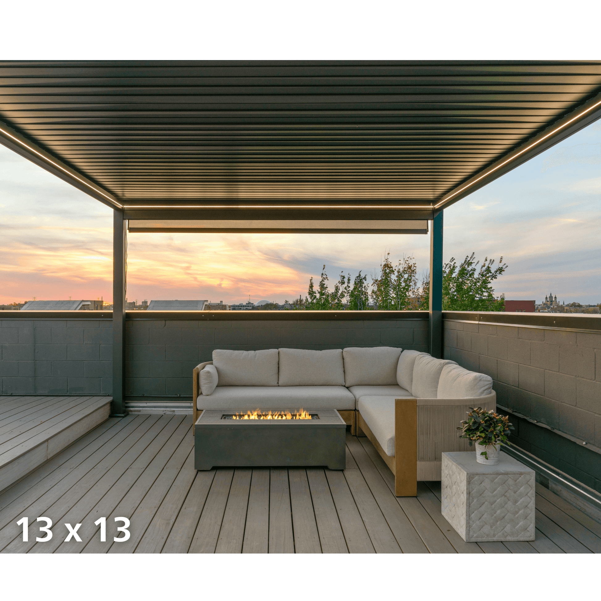 The Bon Pergola 13x13 rooftop lounge features partially open louvers, casting sleek shadow lines below. Its deep gray frame is accented with warm yellow LED strips along the edges, softly lighting the wood deck. Together with the gas firepit, the setup creates a cozy, romantic vibe at dusk.