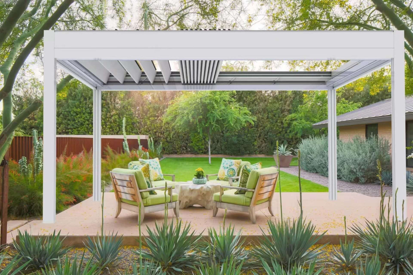 The white Bon Pergola features motorized louvers with white slats and partially visible dark interior components. Surrounded by lush greenery, it creates a relaxing outdoor space perfect for lounging and socializing. The adjustable louvers allow for customizable shade based on sunlight, enhancing comfort and outdoor enjoyment.