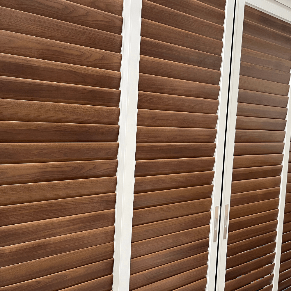 A section of the sliding blinds features white frames and deep brown horizontal slats. The gaps between the slats are smaller, providing better privacy and light blockage when fully closed. These blinds are commonly used to enclose balconies or patios, or as interior partitions, offering both aesthetic appeal and practicality.