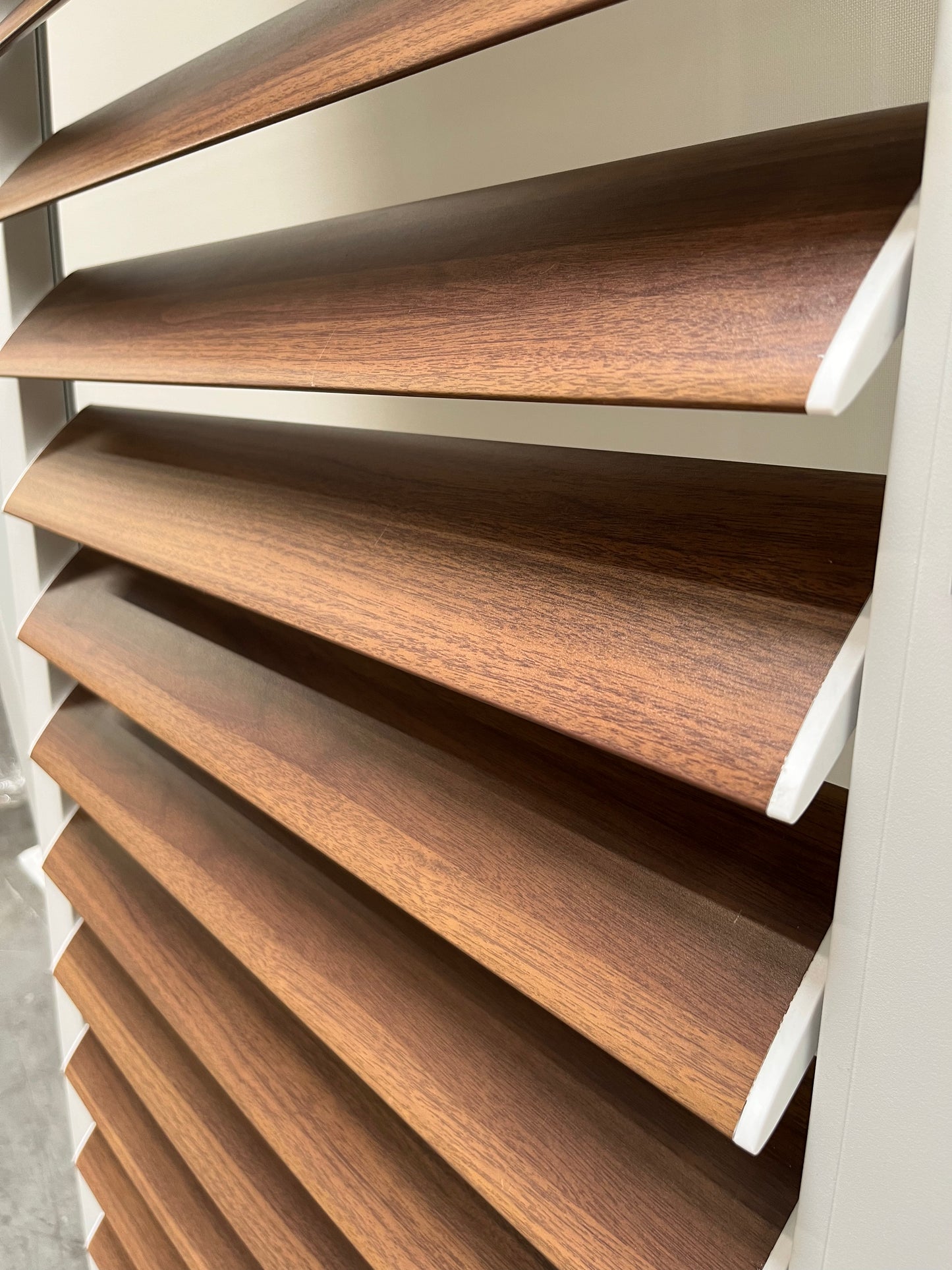 The blinds feature white frames and deep brown horizontal slats. While only the static blinds are shown, their material and design align with the style of sliding blinds. The slats are angled to adjust the amount and angle of light entering the room, while also providing a level of privacy.