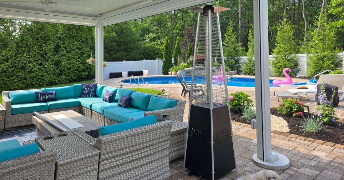 A covered patio with turquoise outdoor sofas, a pool, lounge chairs, garden plants, and a tall patio heater.