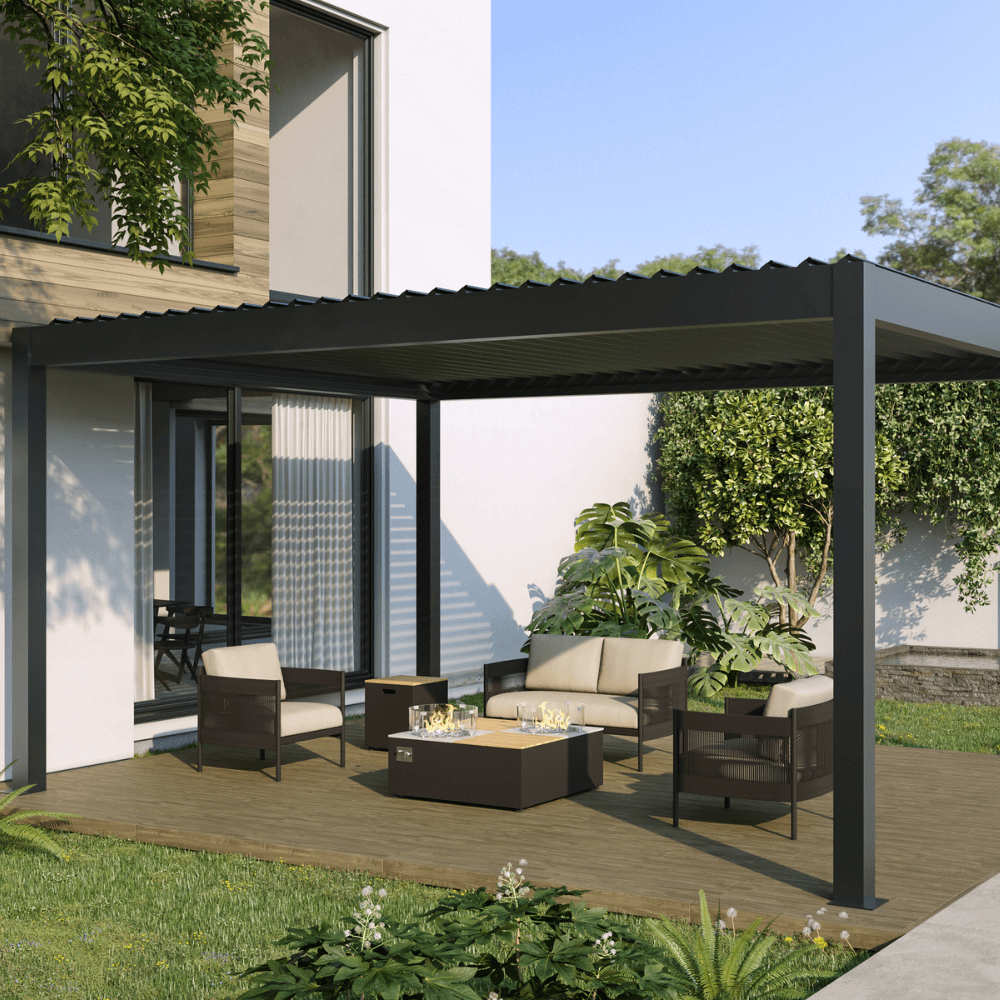 The outdoor lounge area features an electric louvered pergola with the louvers in a closed position, creating a dark, solid roof. The structure is supported by dark, sturdy columns and beams. Beneath the pergola is a modern outdoor furniture set, including a beige loveseat, two dark armchairs with beige cushions, and a dark square gas fire pit coffee table. The fire pit is surrounded by clear decorative stones and encased in a transparent glass wind guard.