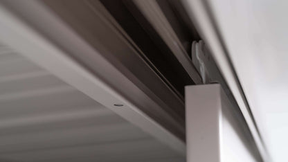 A close-up view of the YODOKO Premium Outdoor Large Shed LMDS by BON PERGOLA showcases its metal rail and white door panel. The focus is on its sleek bracket and mechanism, embodying Japanese craftsmanship with a minimalistic design perfect for modern interiors.