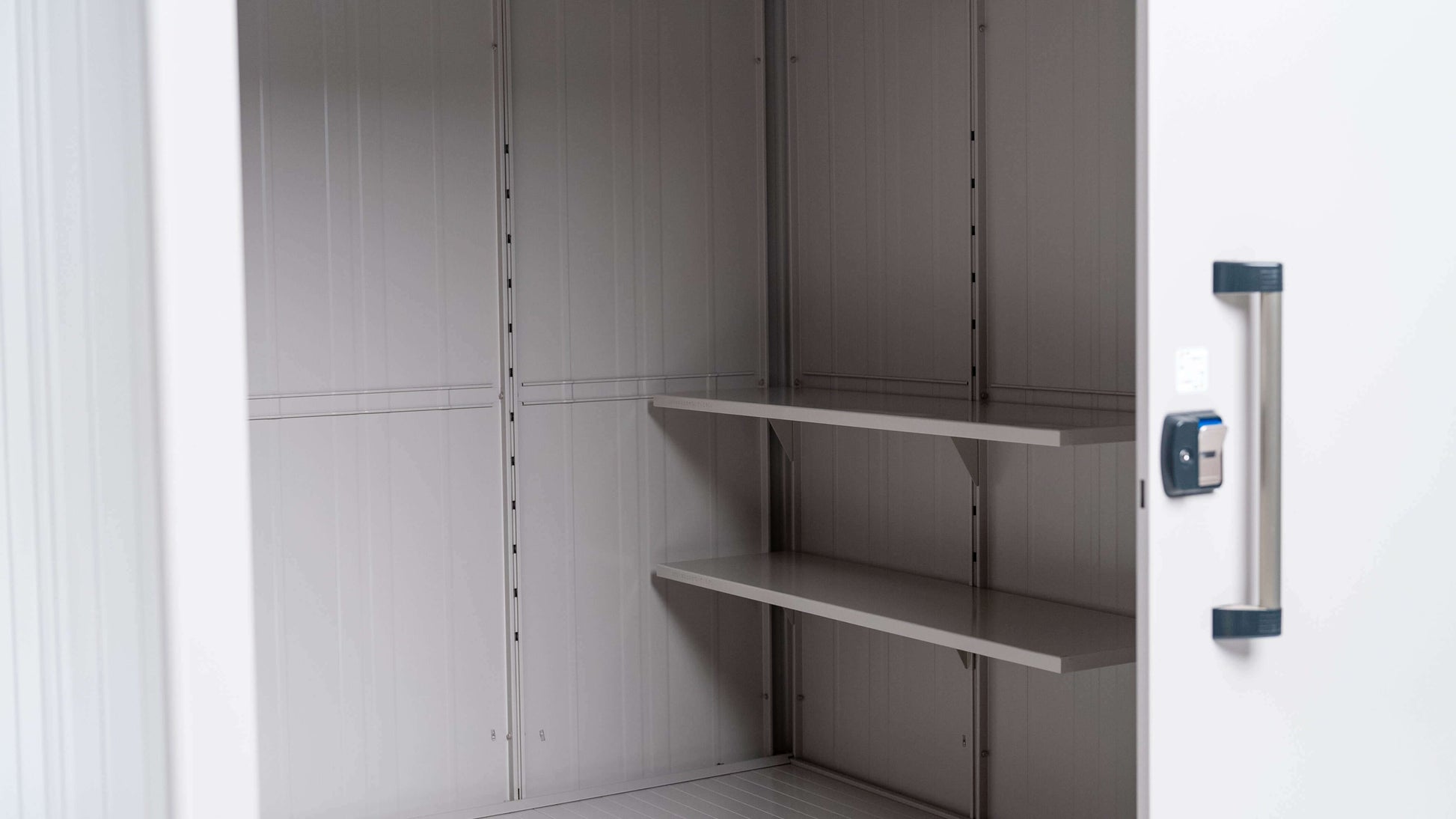 The YODOKO Premium Outdoor Large Shed LMDS by BON PERGOLA features an open design with sleek handles, showcasing Japanese craftsmanship. Inside, two metal shelves mount against a minimalist light gray interior, combining functionality and elegance.