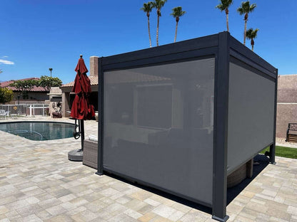 The dark Bon Pergola has a sleek, modern design with a deep gray aluminum frame and a fully closed top, creating a solid gray roof with no gaps between the louvers. It features four wind-resistant gray blinds, all lowered to enclose the space. These thick blinds offer excellent shade, wind protection, and privacy. With clean lines and sturdy construction, it provides a stylish and functional solution for outdoor comfort in any weather.