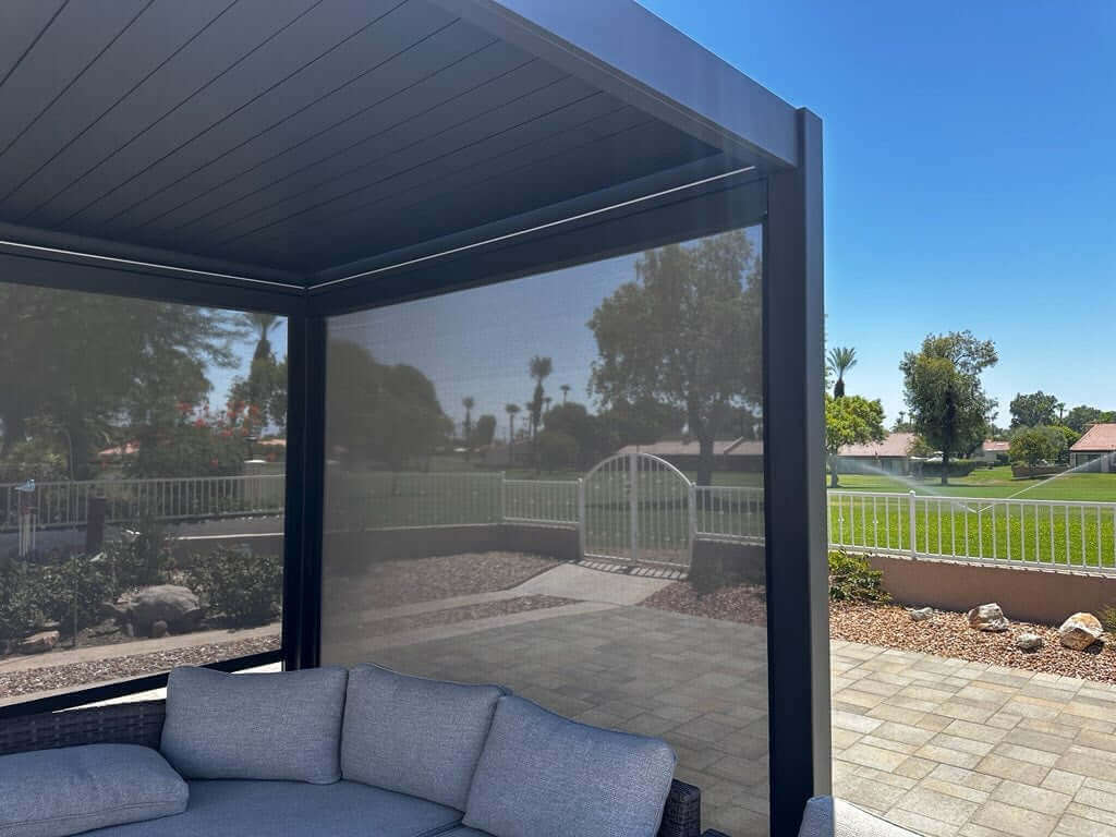 The black square pergola is equipped with four adjustable side sunshades. The dark gray shades are partially lowered, offering both shade and privacy. The material is lightweight yet effectively blocks direct sunlight.