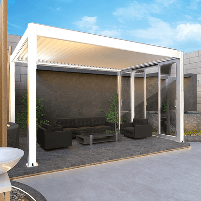 The white pergola features a partially extended shade canopy, revealing white beams and some of the white louvers. Its structure is supported by sturdy white posts and beams in a sleek, modern design. One side includes white-framed sliding glass doors, partially open to connect the space with the surrounding outdoor environment.