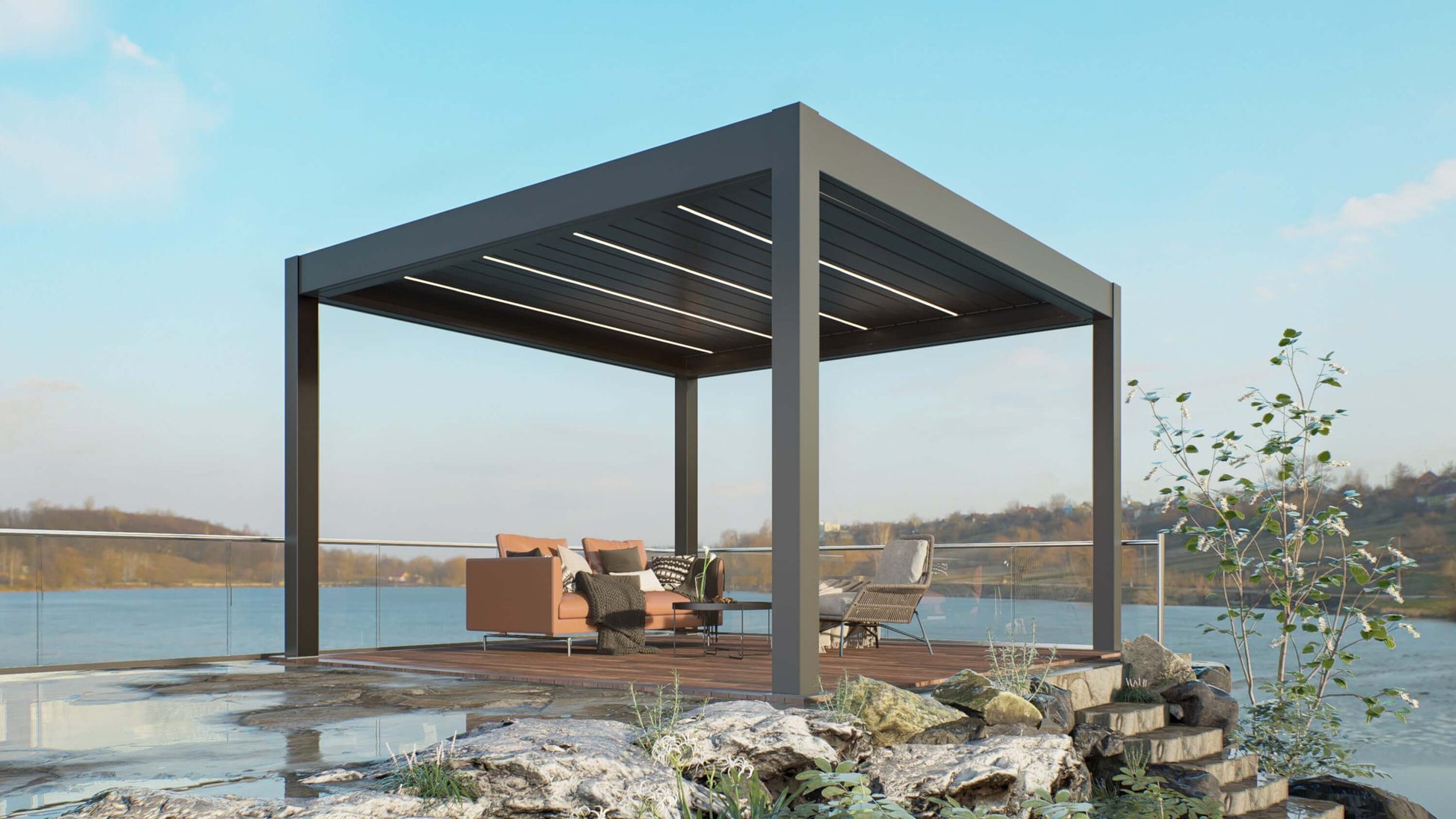 A dark gray pergola with partially open louvers sits above a platform decked in rich brown wood, right by the water’s edge. Beneath the pergola is a set of modern outdoor furniture, including a brown sofa, two light brown woven armchairs, and a small side table—creating a cozy, stylish space for waterfront relaxation.