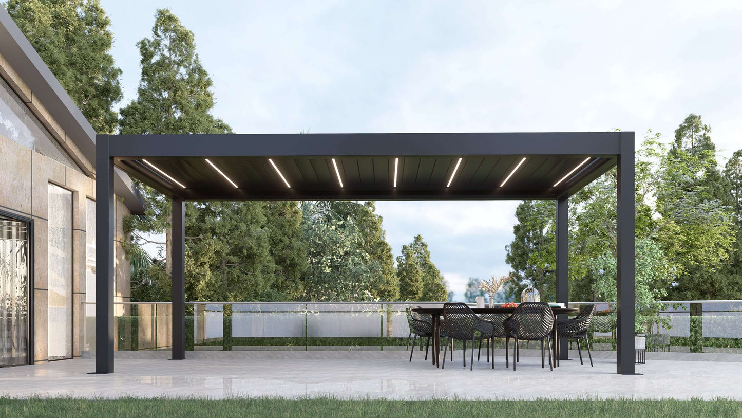 A dark gray Bon Pergola with a motorized louvered roof and integrated LED lighting sits on a light gray paved patio, surrounded by tall green trees. The louvers are partially open, revealing deep gray slats with built-in white LED strips that remain visible even in daylight. The pergola’s clean, modern design features sturdy dark gray beams and posts, creating a sleek and stylish outdoor space.